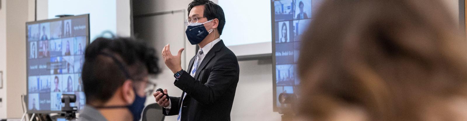 lecture in a hybrid classroom with the professor and students with masks