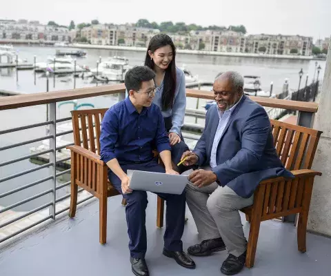 Faculty member explaining to a seated student with a laptop