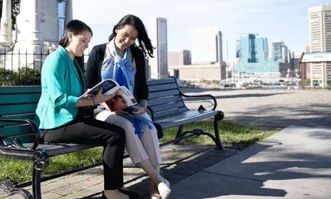 two students seated on a bench near Carey sharing a catalogue