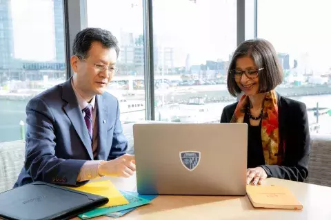 doctor in lab coat at laptop with tablet