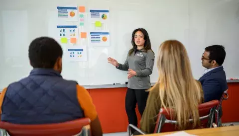 instructor at board in front of three seated students