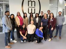 MSM Media Works students in a group pose with MW logo in background