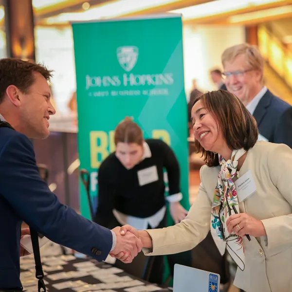 Two people shaking hands at the welcome table during a Human Capital Development Lab event.