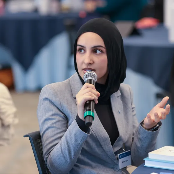 Student in hijab speaking into a microphone at a conference