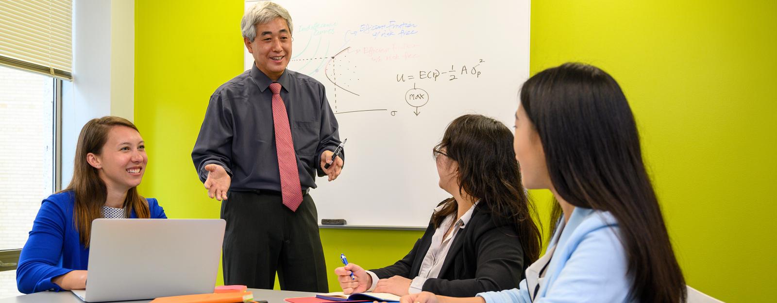 professor teaching three students in the classroom