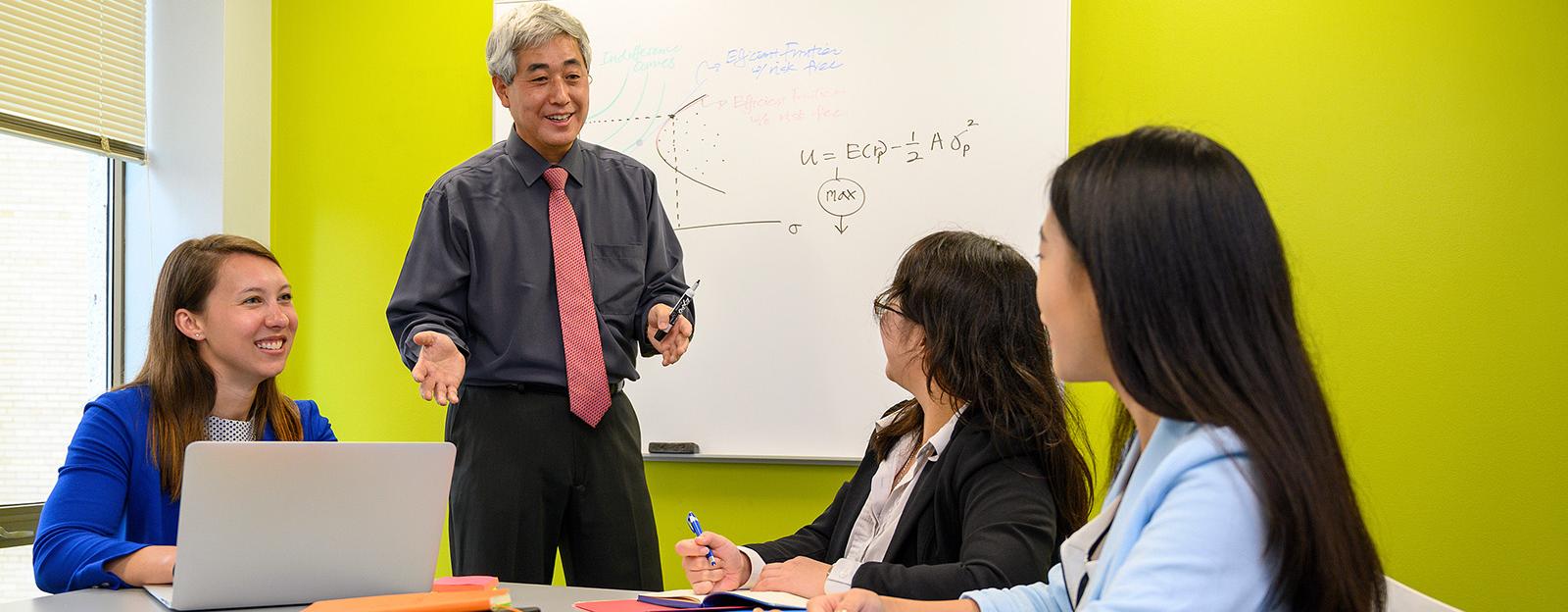 professor teaching three students in the classroom